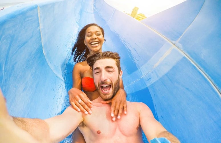 Young happy friends having fun in aqua park pipe