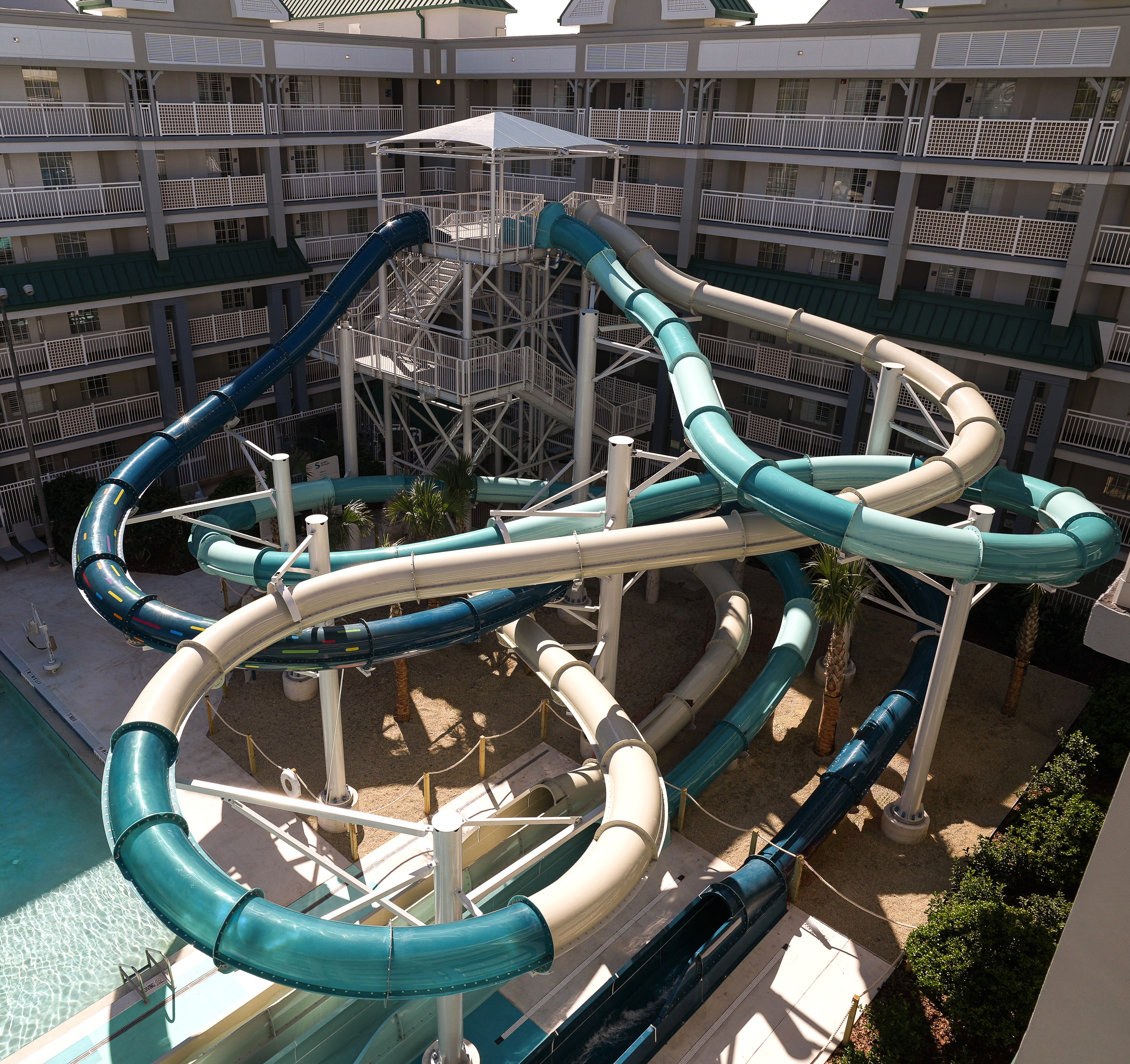 Three water slides of various shapes and length, descend from a singular launch tower.