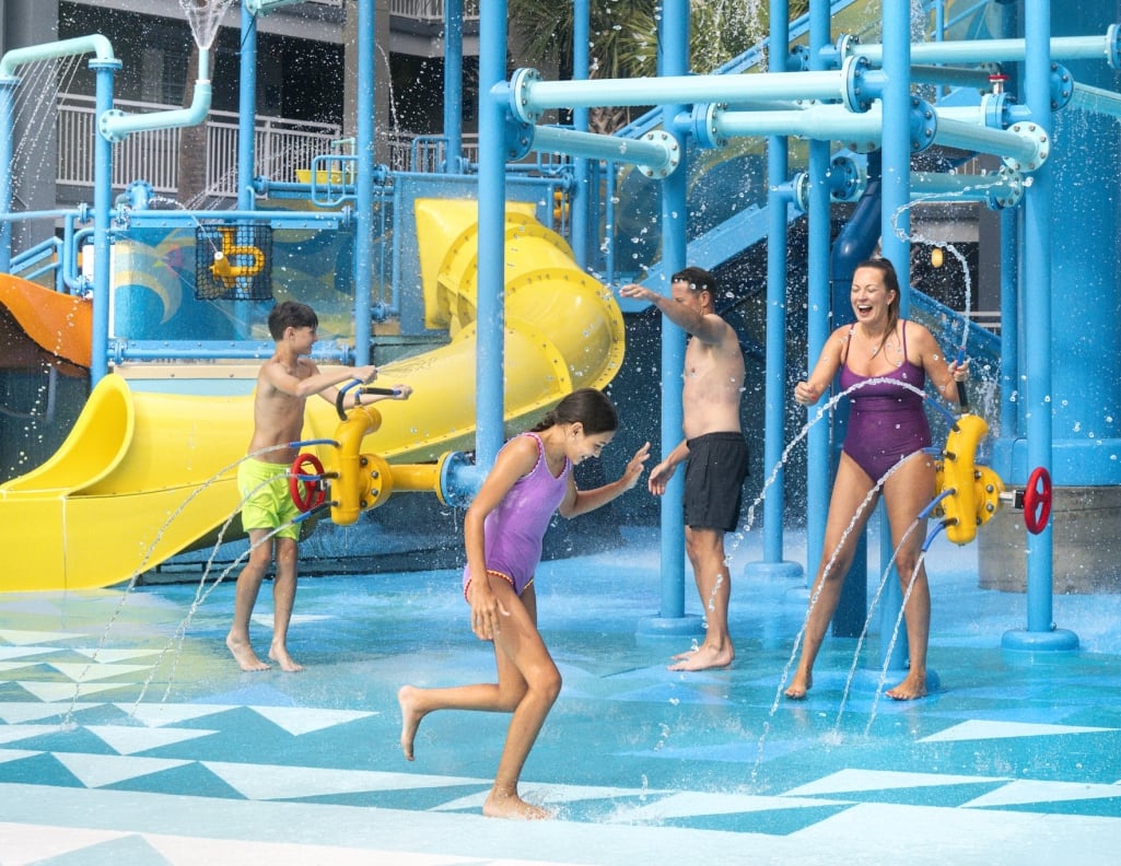 A family of four playing on the Aqua Cove playground