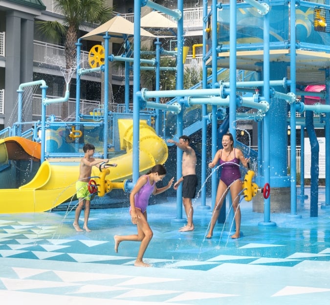A family of four playing on the Aqua Cove playground