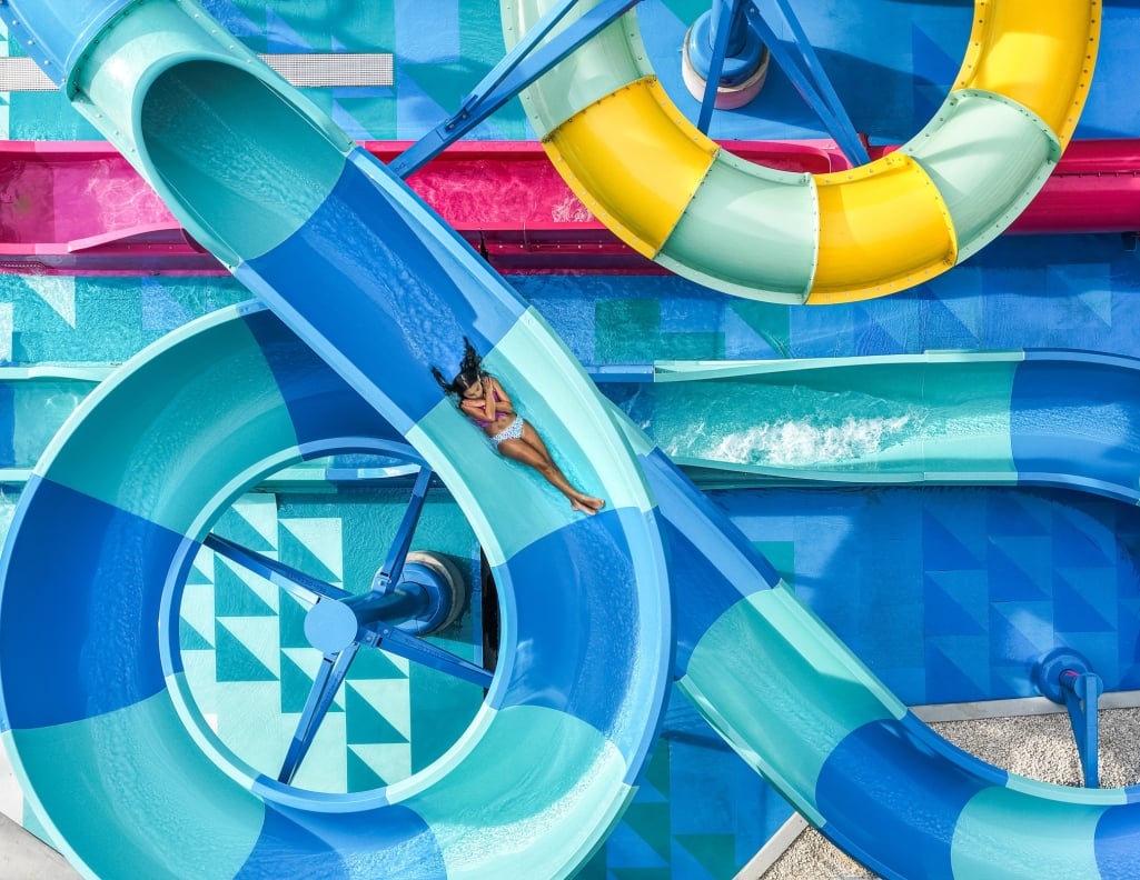 A girl flys down a blue striped water slide.