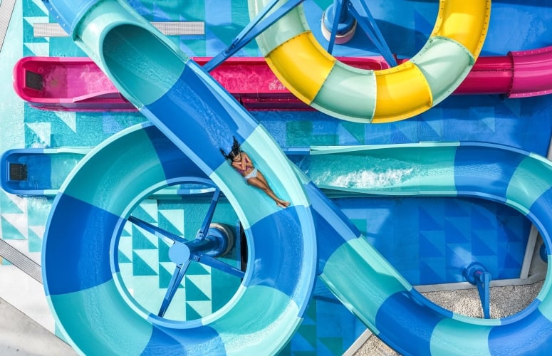 A girl flys down a blue striped water slide.
