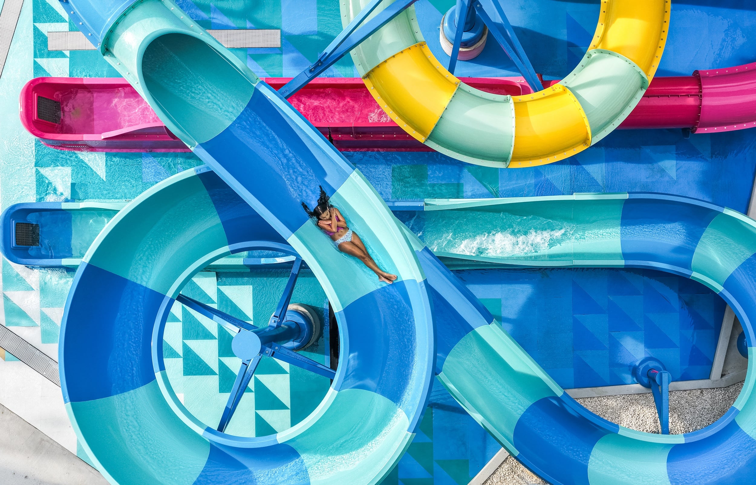 A girl flys down a blue striped water slide.
