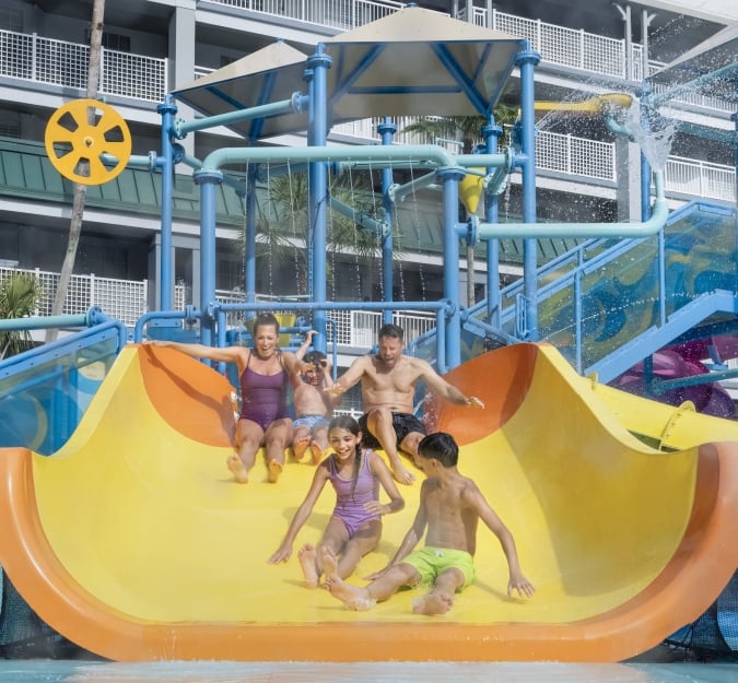 A family of five riding the large yellow slide together