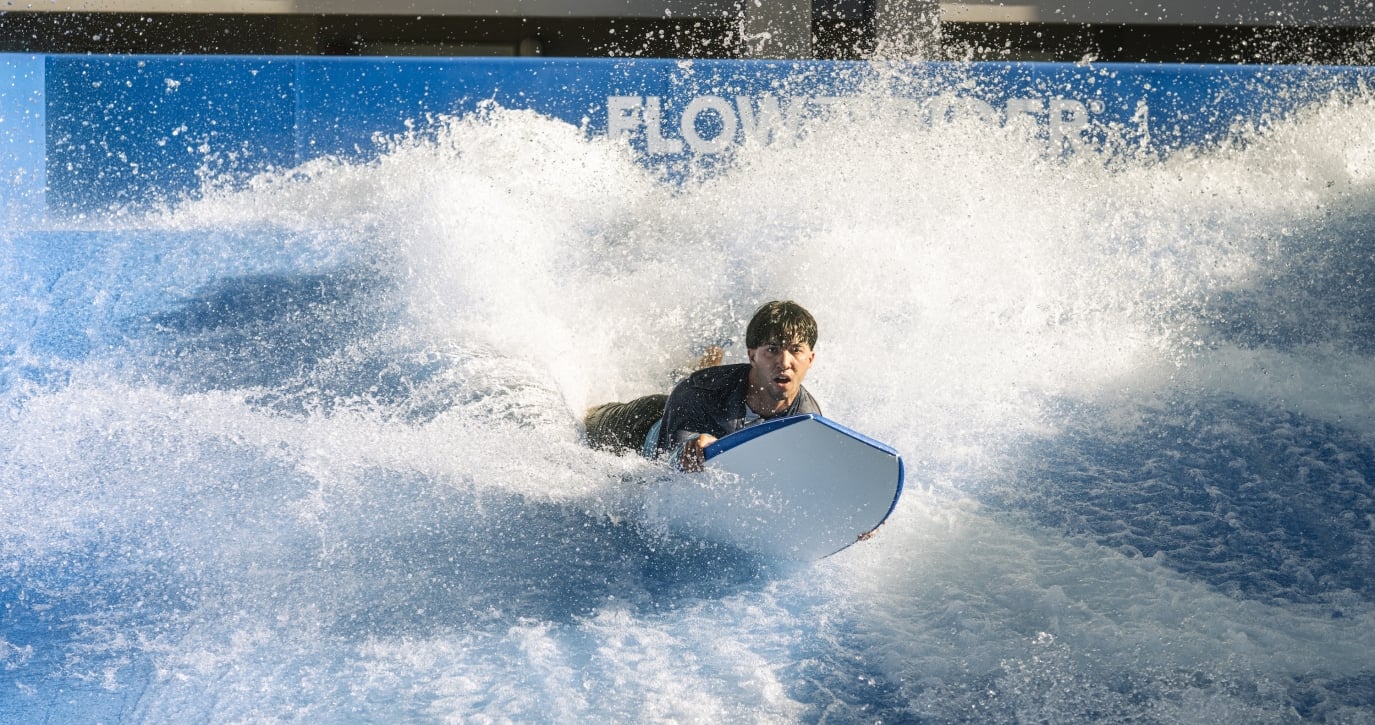 A man riding the Flowrider with his board