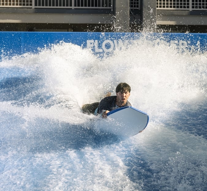 A man riding the Flowrider with his board