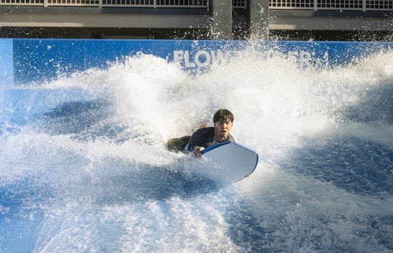 A man riding the Flowrider with his board