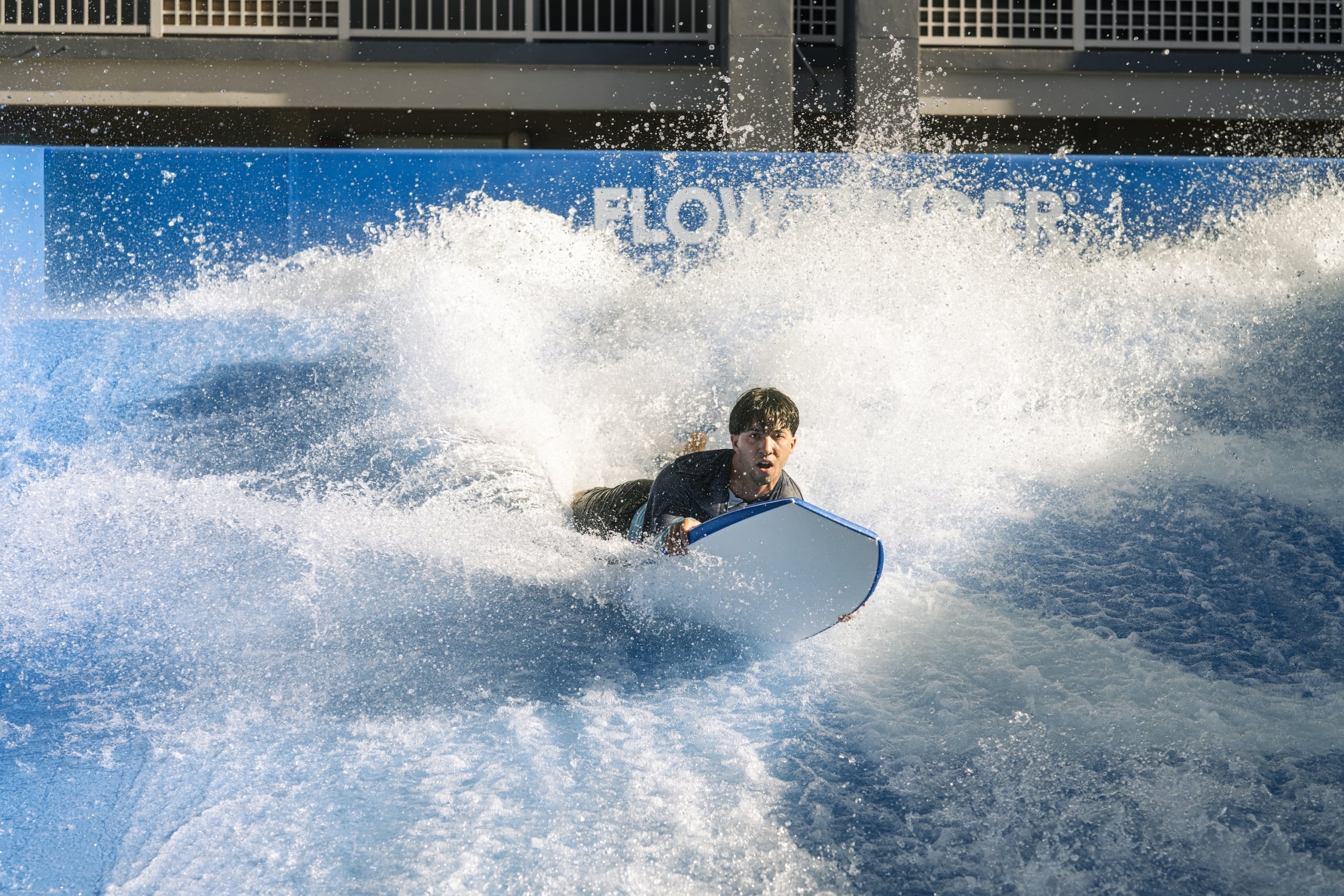 A man riding the Flowrider with his board