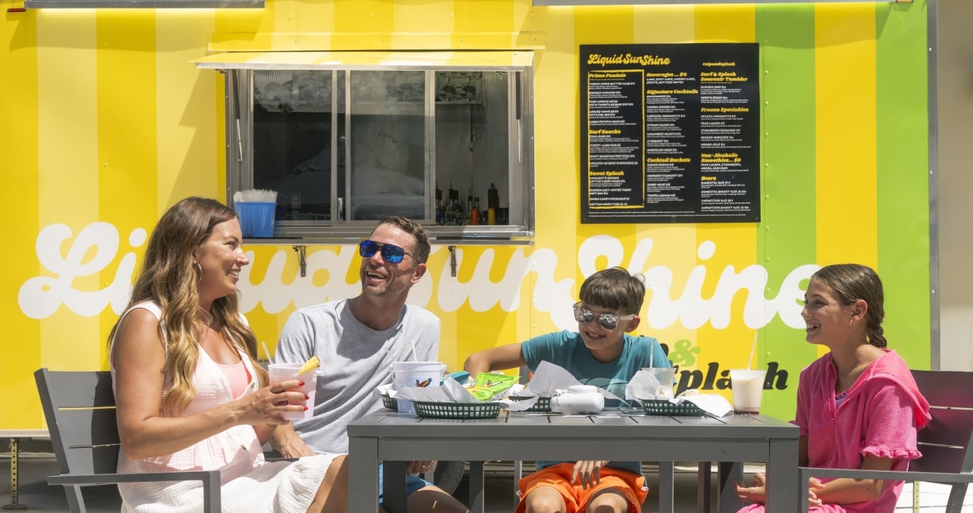 A family of four dines beside the Liquid Sunshine food truck