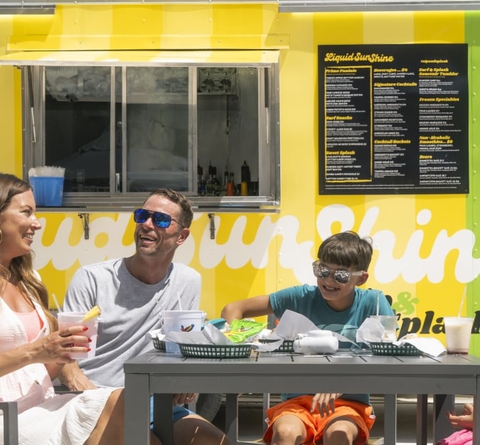 A family of four dines beside the Liquid Sunshine food truck
